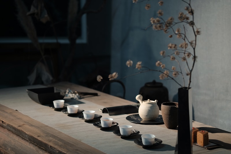 A tea set with small white cups and a teapot on a wooden table