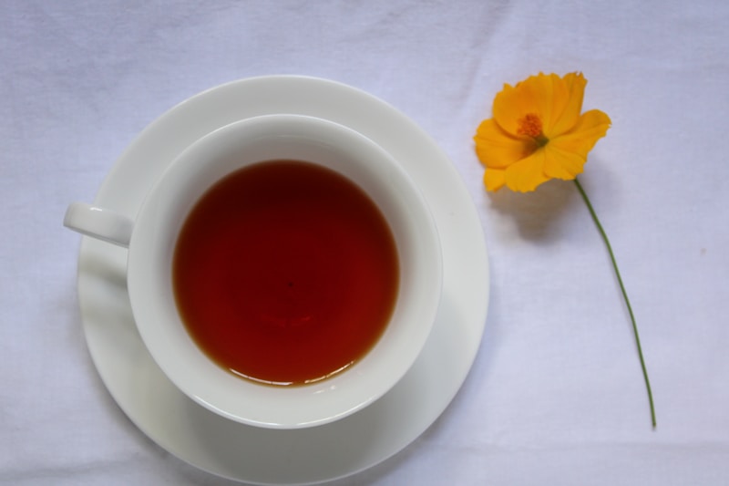 A cup of tea next to a yellow flower