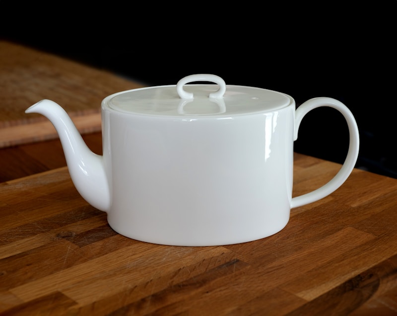 A white tea pot sitting on top of a wooden table