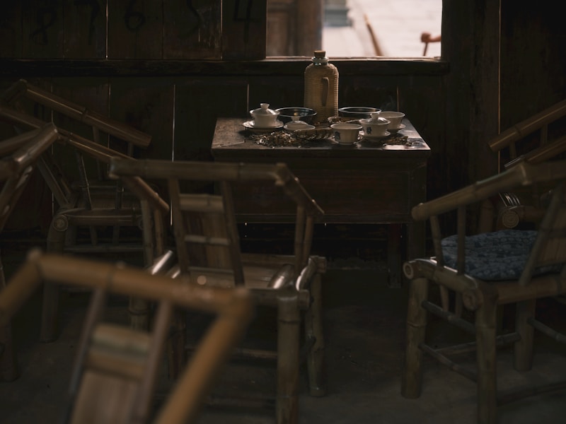 Wooden chairs surround a table with tea set